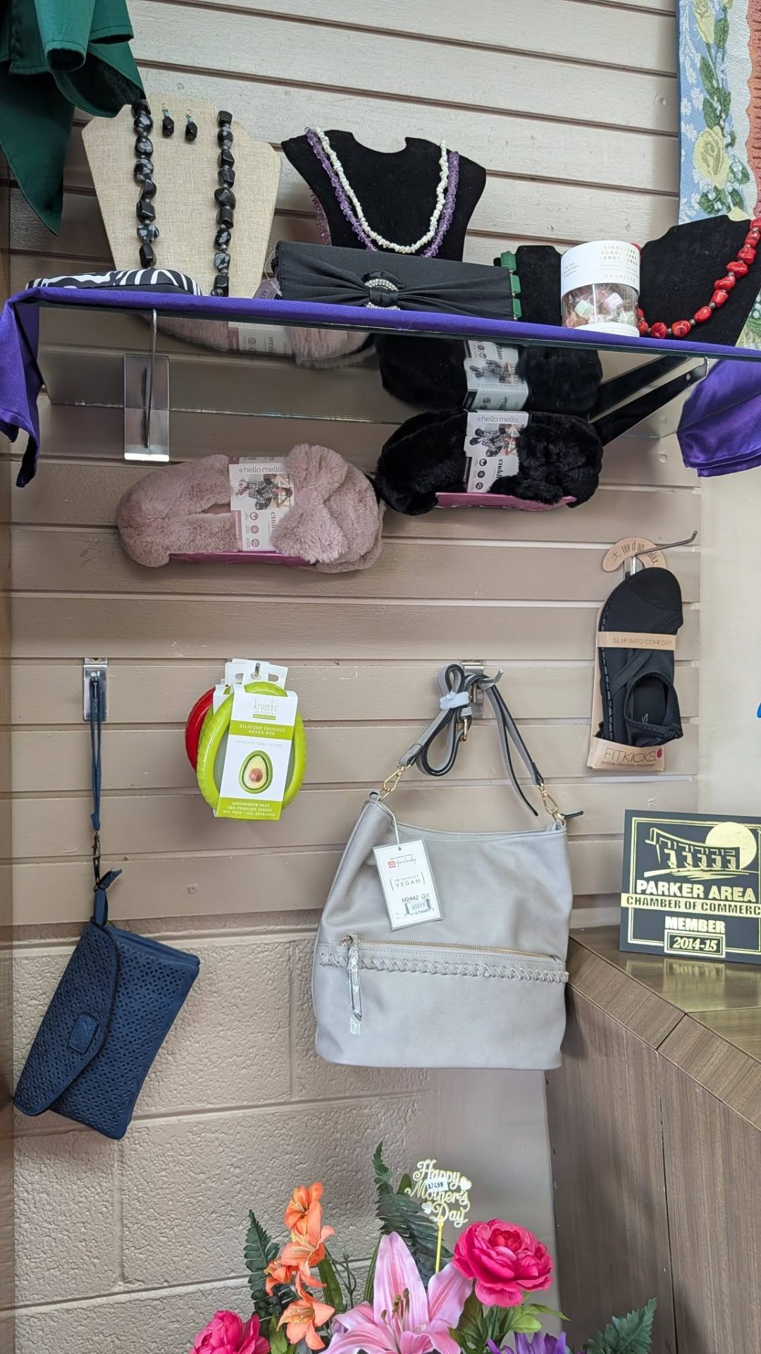 Necklaces, handbags, fuzzy slippers, and giftware on slat wall display.